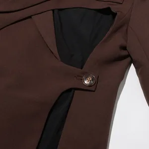 Close-up view of the irregular hollow-out design and tortoise button on a brown blazer jacket
