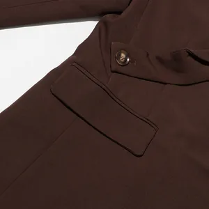 Detailed macro view of the flap pocket and button on a premium dark brown British blazer