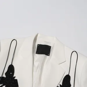 Detailed view of white blazer featuring black sequined butterfly applique design