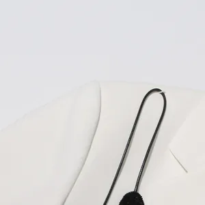 Detailed view of an elegant white blazer featuring a black sequin bow accessory