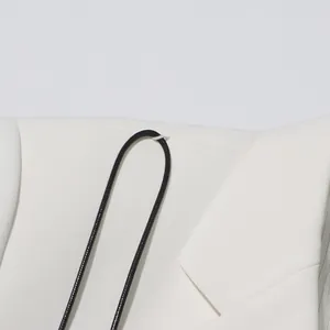 Detailed view of a white elegant blazer featuring a black decorative cord and fabric texture.