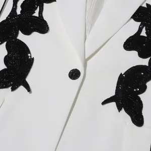 Detail of white blazer featuring black sequined butterfly patches and single button