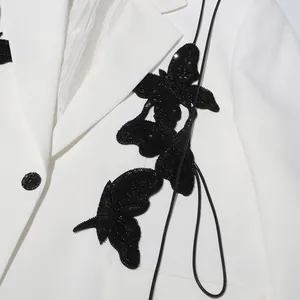 Detail of white blazer with black sequined butterfly patch and single button design
