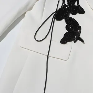 Detailed close-up view of black sequined butterfly appliqué on a premium white blazer