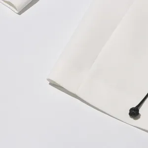Detail shot of white high-end blazer sleeve featuring black knotted cord decoration