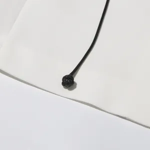Detailed close-up of a black braided cord knot on an elegant white blazer jacket