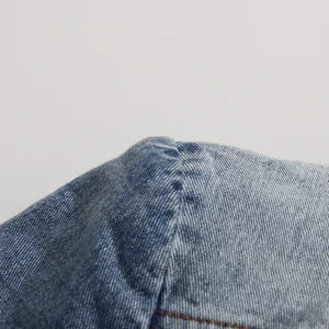 Detailed macro view of blue washed denim fabric texture and premium stitching details.