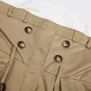 Detalle del vestido palabra de honor caqui con botones de doble botonadura y pliegues