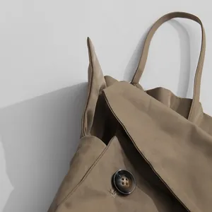 Close-up of khaki jumpsuit fabric showing shoulder strap and large resin button detail