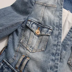Detailed close-up of a vintage blue denim blazer with a golden lion head button.