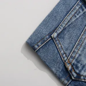Close-up detail showing the high-quality stitching on a distressed blue denim blazer