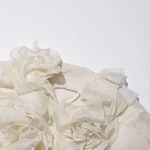 Detailopname van de elegante gebroken witte chiffonruches en bloemmotieven op deze Franse jurk.