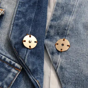 Close-up of gold-tone metal snap button fasteners on a distressed blue denim blazer