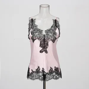 Detail of a pink silk camisole featuring delicate black eyelash lace trim at the hem.