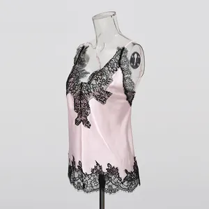 Close-up detail of a pink satin camisole featuring elegant black floral lace trim accents
