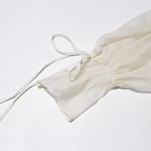 Detailopname van de witte chiffon mouw met verstelbaar strikje en knoopje voor dames