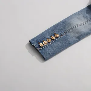 Close-up of distressed denim blazer sleeve with decorative gold embossed buttons