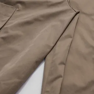 Macro close-up of the khaki fabric texture and fine seam detailing of the wide-leg jumpsuit
