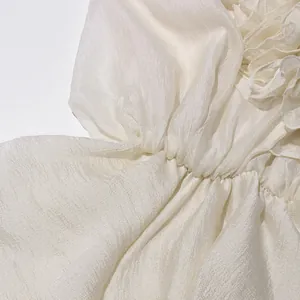 Detailopname van de delicate ruches op een crèmekleurige chiffon jurk in Franse stijl