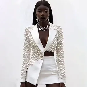 Dettaglio di lussuoso set blazer e gonna bianchi con scollo a V decorati con perle
