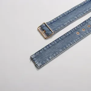 Detail showing a distressed blue denim belt with a polished gold metal buckle and eyelets.