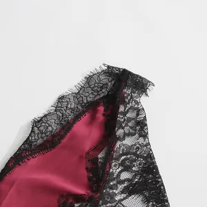 Macro detail of exquisite black floral eyelash lace trim on a deep red satin camisole