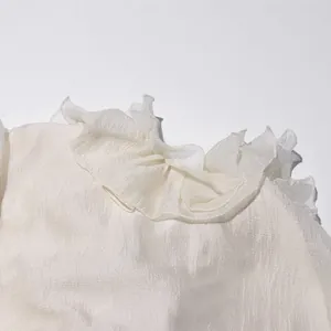 Close-up van de delicate ruffelkraag op een witte chiffon blouse met verfijnde textuur.