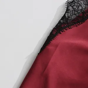 Close-up detail of black lace trim on a burgundy silk V-neck camisole top