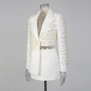 Elegante set bianco con blazer irregolare e gonna con ricche decorazioni in perline.