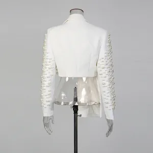 Dettaglio di un blazer corto bianco con elaborate decorazioni di perle sulle maniche