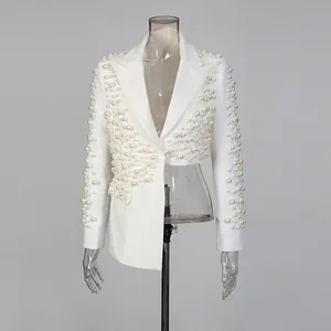 Dettaglio di blazer bianco asimmetrico con lussuose decorazioni in perle a mano