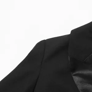 Close-up detail of the shoulder and satin lapel on a black luxury blazer dress.