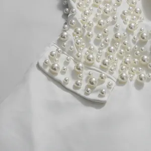 Dettaglio ravvicinato di raffinati decori di perle bianche su un elegante completo gonna