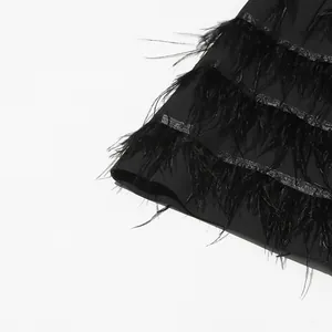 Close-up detail of the elegant black ostrich feather trim on a luxury suit dress hem