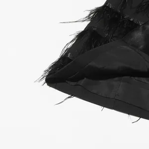 Detailed macro view of an elegant black dress featuring ostrich feather trim and satin fabric