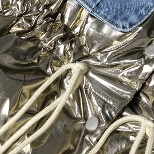 Gedetailleerd overzicht van modieus metallic goud vest met blauwe denim patchwork en trekkoord