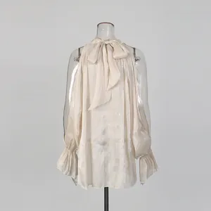 Detailansicht der champagnerfarbenen Chiffonbluse mit Schleifenhals und Cut-outs.