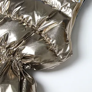 Detailweergave van gouden metallic stoftextuur van een modieus gewatteerd vestje