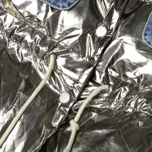 Detail van metallic zilveren gewatteerde bodywarmer met denim kraag en trekkoord