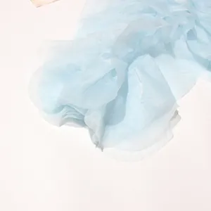 Nahaufnahme des hellblauen Chiffonstoffs mit Rüschendetails an einer Sommerbluse