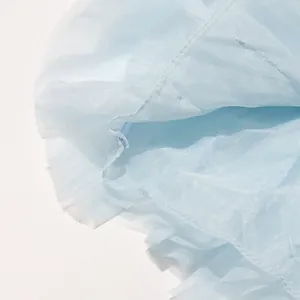 Detailaufnahme der transparenten Textur und des Rüschensaums einer hellblauen Bluse