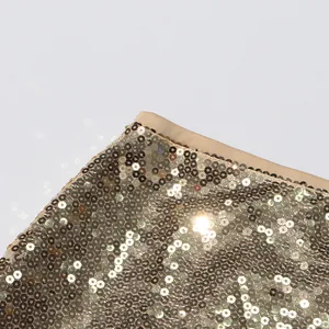 Nahaufnahme der schimmernden Goldpailletten auf elegantem Abendrock mit hoher Taille