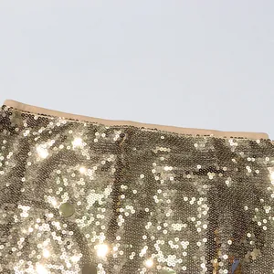 Detail eines goldfarbenen Paillettenrocks mit hoher Taille und Metallreflexionen