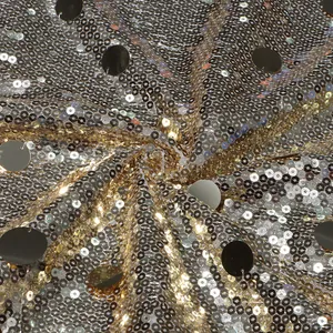 Detaillierte Makroansicht von glänzendem Paillettenstoff in Gold und Silber mit Metallscheiben.