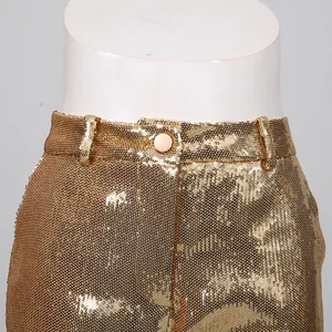 Detailed close-up view of gold sequined high-waisted trousers with elegant button closure.