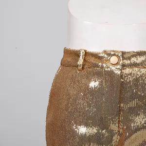 Close-up showing the intricate gold sequin texture and button on high-waist trousers