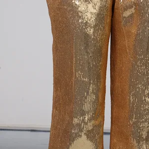 Macro detail of high-quality gold shimmering sequins on elegant wide-leg evening trousers.