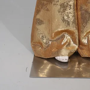 Close-up detail showing the shimmering gold sequin texture of high-end fashion trousers