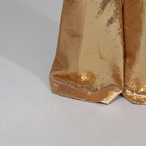 Detail macro shot of high-density golden sequins on the bottom of wide-leg trousers