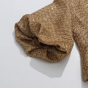 Detailed macro shot of gold sequined tweed puff sleeve on elegant French style jacket